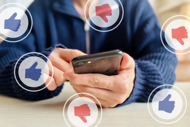 スマートフォンを持つ男性、グッドボタンとバッドボタン